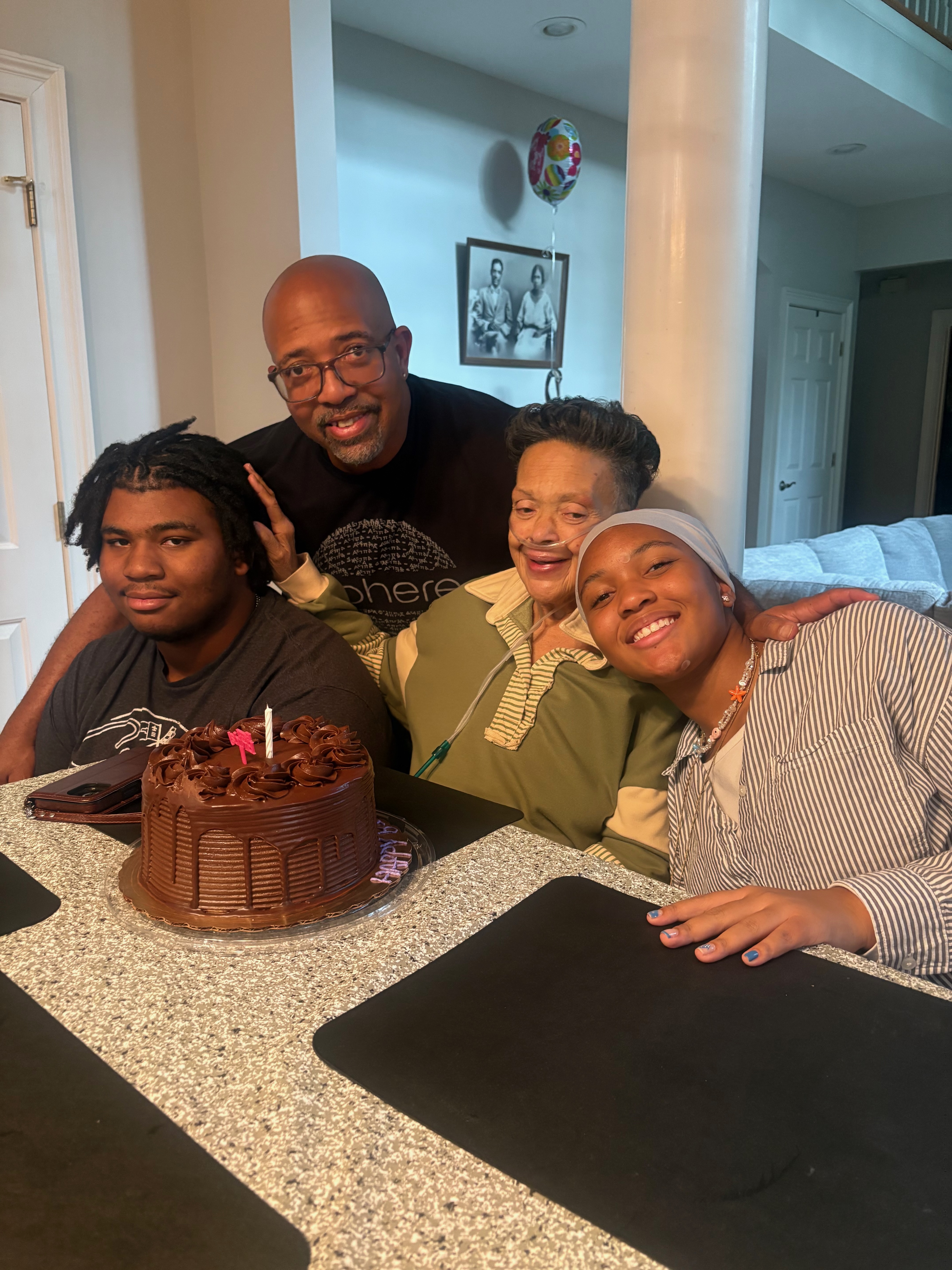 Karen with her son and grandchildren around a chocolate birthday cake