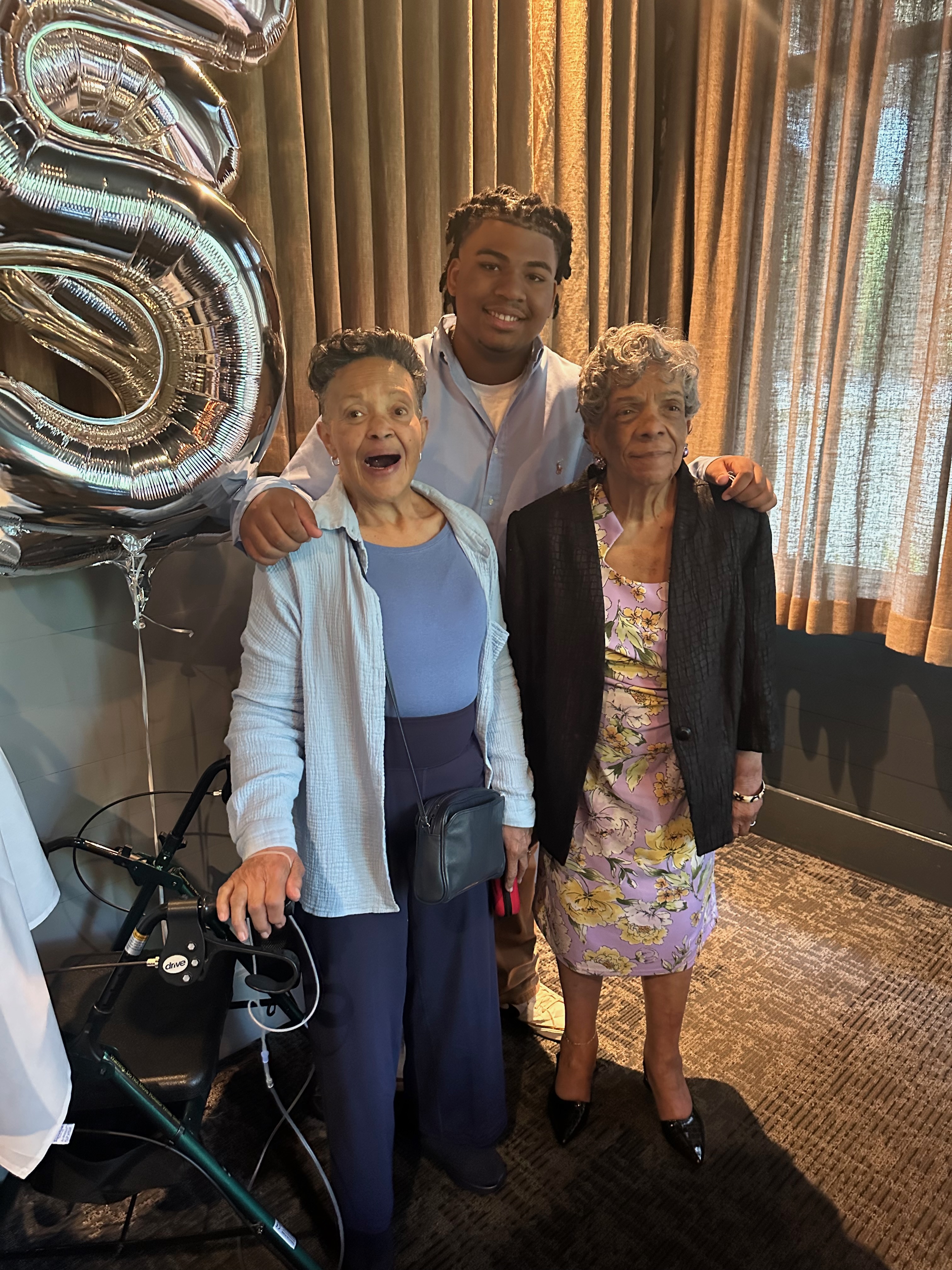 Karen laughing with family beside silver birthday balloons